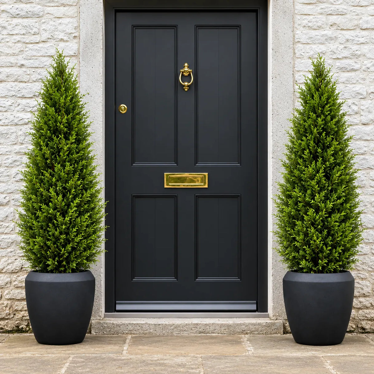 Pair of 150cm UV-resistant artificial Cypress Tower trees in black Norfolk planters framing a luxury black front door with brass fittings.